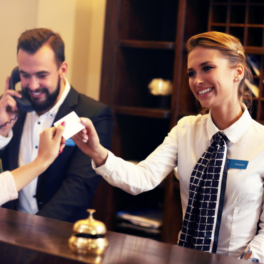 Deux réceptionnistes en hôtel reçoivent un client.