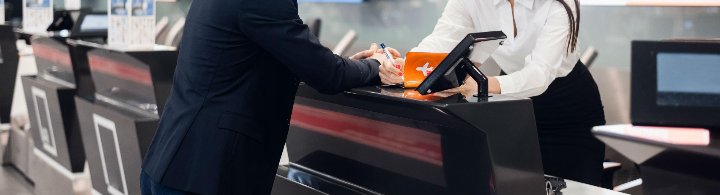 un passager et un agent discutent au comptoir d'enregistrement d'un aéroport